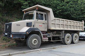 An old truck with a trailer parked on the side of the road. On the side of the road is a hill full of trees and grass. - TAB Bank